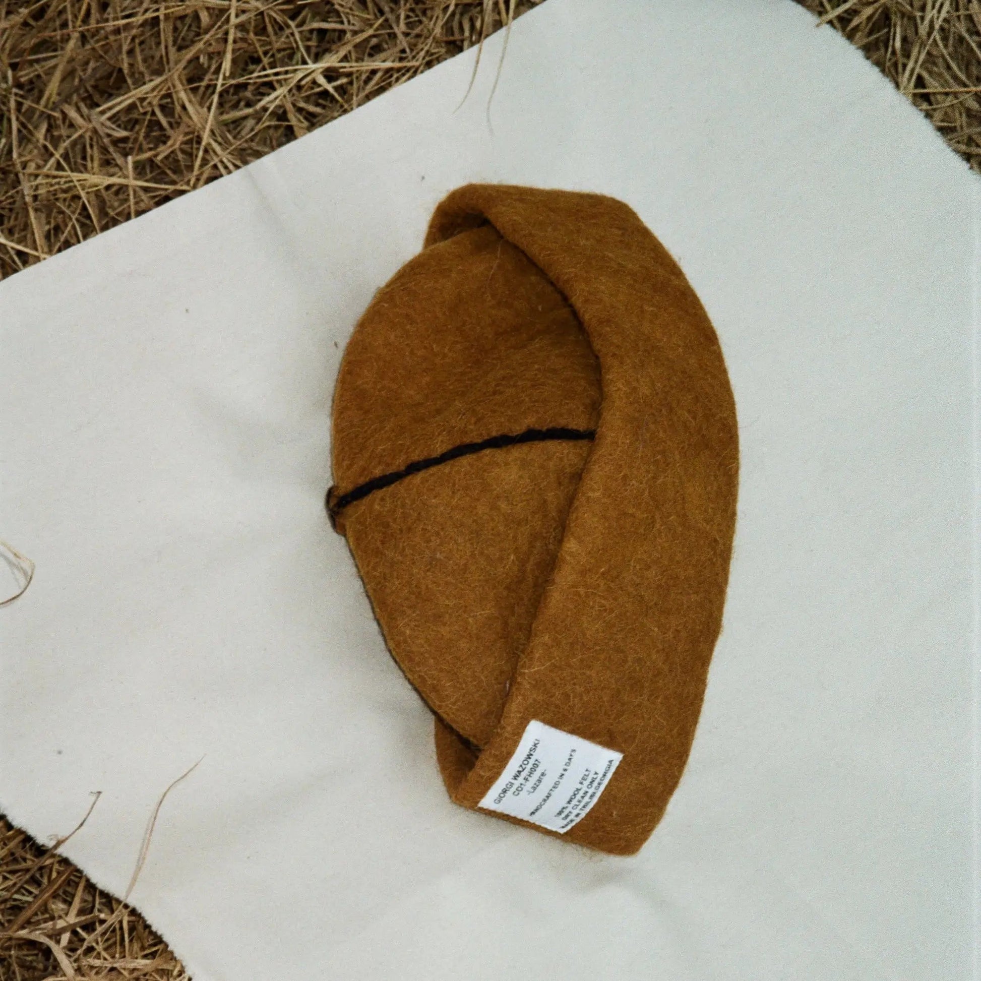 Folded Tobacco wool felt hat, showcasing its warm brown wool and refined stitching